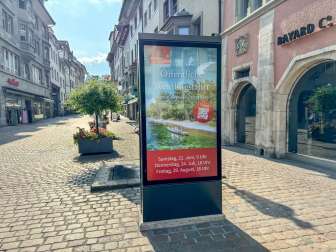 Auf einem digitalen Screen in einer Stadt wird Werbung für eine öffentliche Weidlingsfahrt gemacht.