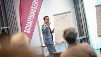 Ein Mann steht vor einem Publikum. Er schreibt auf ein Flipchart.