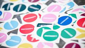 Es liegen viele bunte und runde Sticker auf einem Tisch. Auf den farbigen Hintergründen ist das Logo des Schaffhauserlandes.