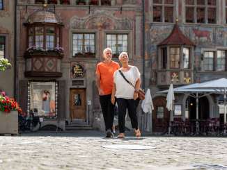 Zwei Personen laufen über den rathausplatz Stein am Rhein. Im Hintergrund sind die weltberühmten Fassadenmalereien.