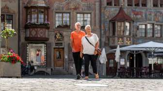 Zwei Personen laufen über den rathausplatz Stein am Rhein. Im Hintergrund sind die weltberühmten Fassadenmalereien.